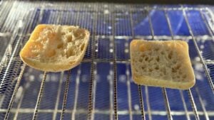 Two halves of a fresh ciabatta roll resting on a cooling rack before toasting.