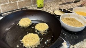 Golden panko-crusted eggplant slices frying in a cast iron skillet.
